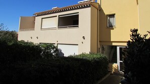 A two-story building with a flat roof and beige walls. There are multiple windows, some with shutters, and a small balcony on the upper floor. - 40m² apartment ideal for 2 or 4.  50 m from the sea. quiet area. (Agde)
