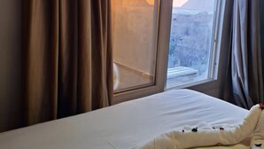 A hotel room with a bed, curtains, and a window offering a view of a pyramid. - Topaz Pyramids view inn  (Giza)