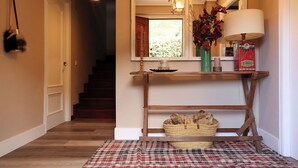 A hallway with a wooden console table, a mirror, a lamp, and a basket with items. - Luxury House in Picos de Europa Liebana garden with chill out area (La Frecha)