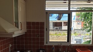 Una cocina con armarios blancos, una estufa a gas, un fregadero y una ventana con vistas a edificios.
