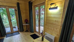 Een houten interieur met een houten tafel, een kleine tafellamp en uitzicht op groen buiten.