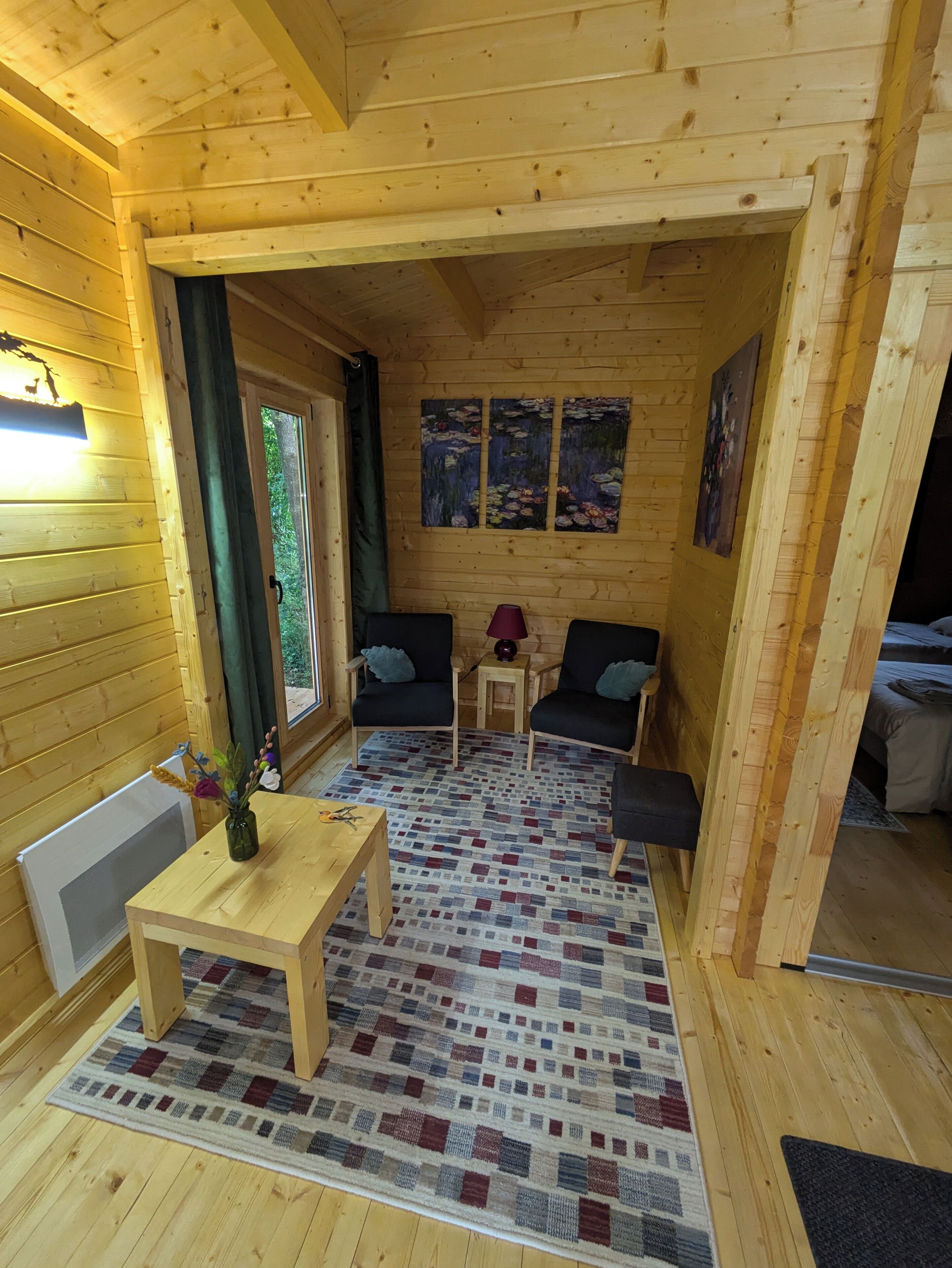 L’intérieur d’un chalet en bois chaleureux et accueillant, avec une petite table à manger, deux canapés et un tapis à motifs.