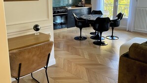 A modern kitchen with a stove, oven, and dining area with chairs and a table. - Apartment nestled in the trees  (Narbonne)