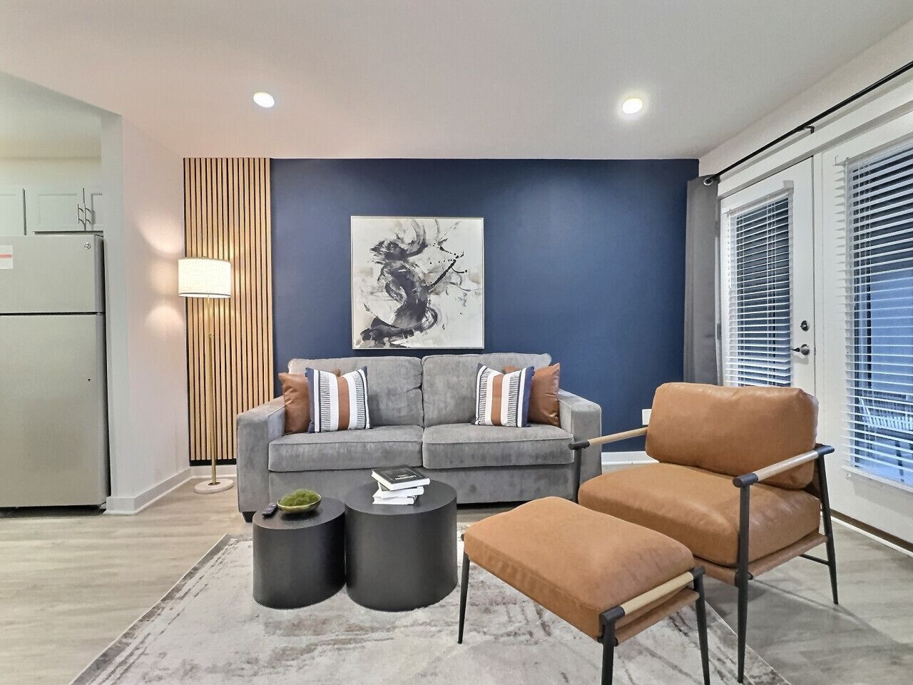 A modern living room with a grey sofa, a brown armchair, and two black side tables.