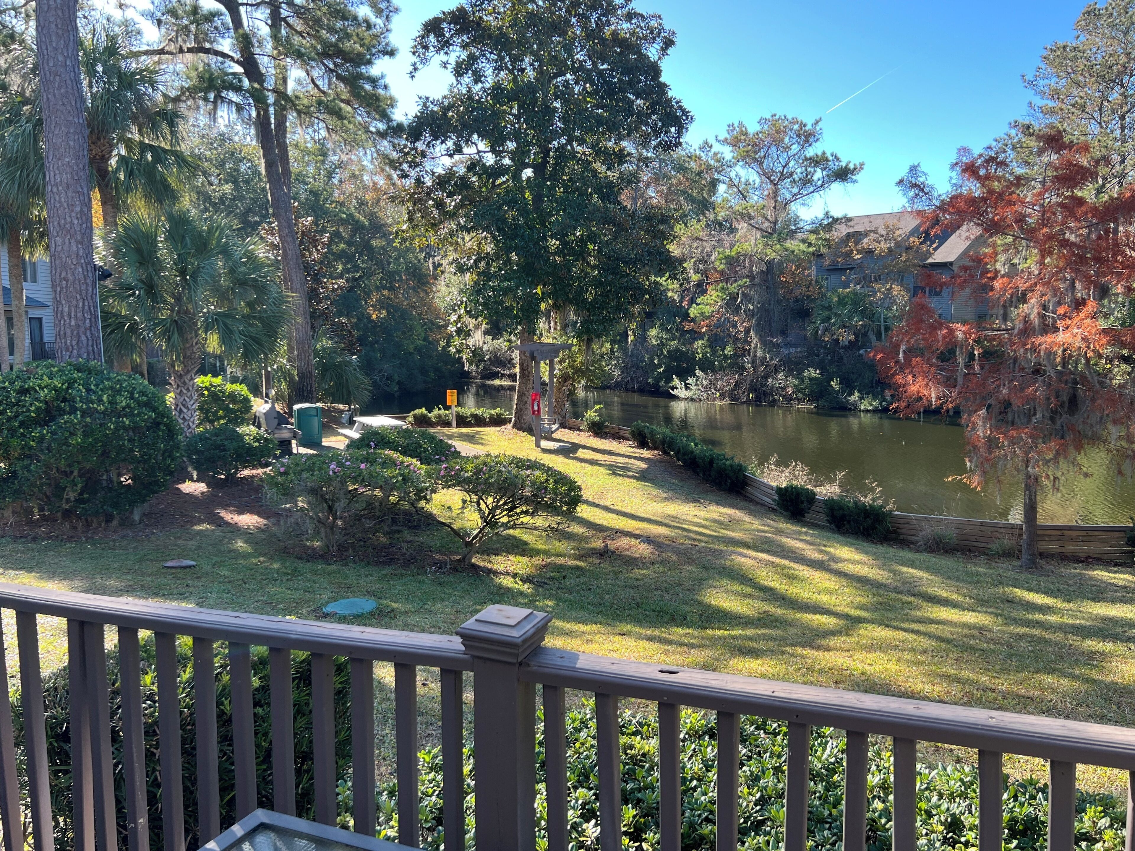 Une vue d’un parc avec un étang, entouré d’arbres et doté d’une terrasse en bois.