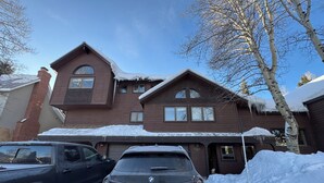 A two-story house with a brown exterior, a garage, and a snow-covered driveway. - Spacious 6-bedroom 6.5 bath house in charming Crested Butte with gym and hot tub (Crested Butte)
