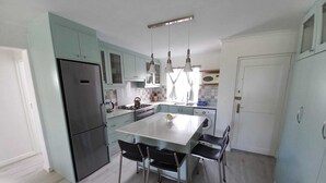 A modern kitchen with light blue cabinets, stainless steel appliances, and a central island with chairs. - Cosy apartment by the ocean, located in a family friendly town. (Hermanus)