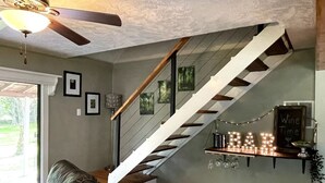 Un salon moderne avec un escalier, un ventilateur de plafond et un coin bar à vin.