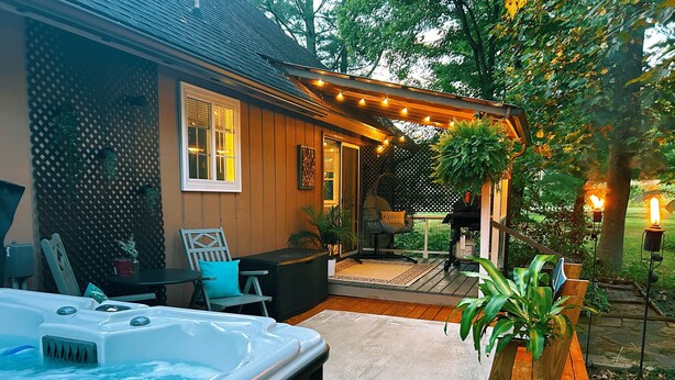 Une terrasse en bois avec un jacuzzi, des sièges d’extérieur et des guirlandes lumineuses.