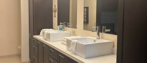 A modern bathroom with two white sinks, dark cabinets, and a large mirror.