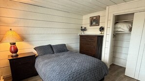 Une chambre à coucher comprenant un lit, une table de chevet avec une lampe, une commode et une armoire.