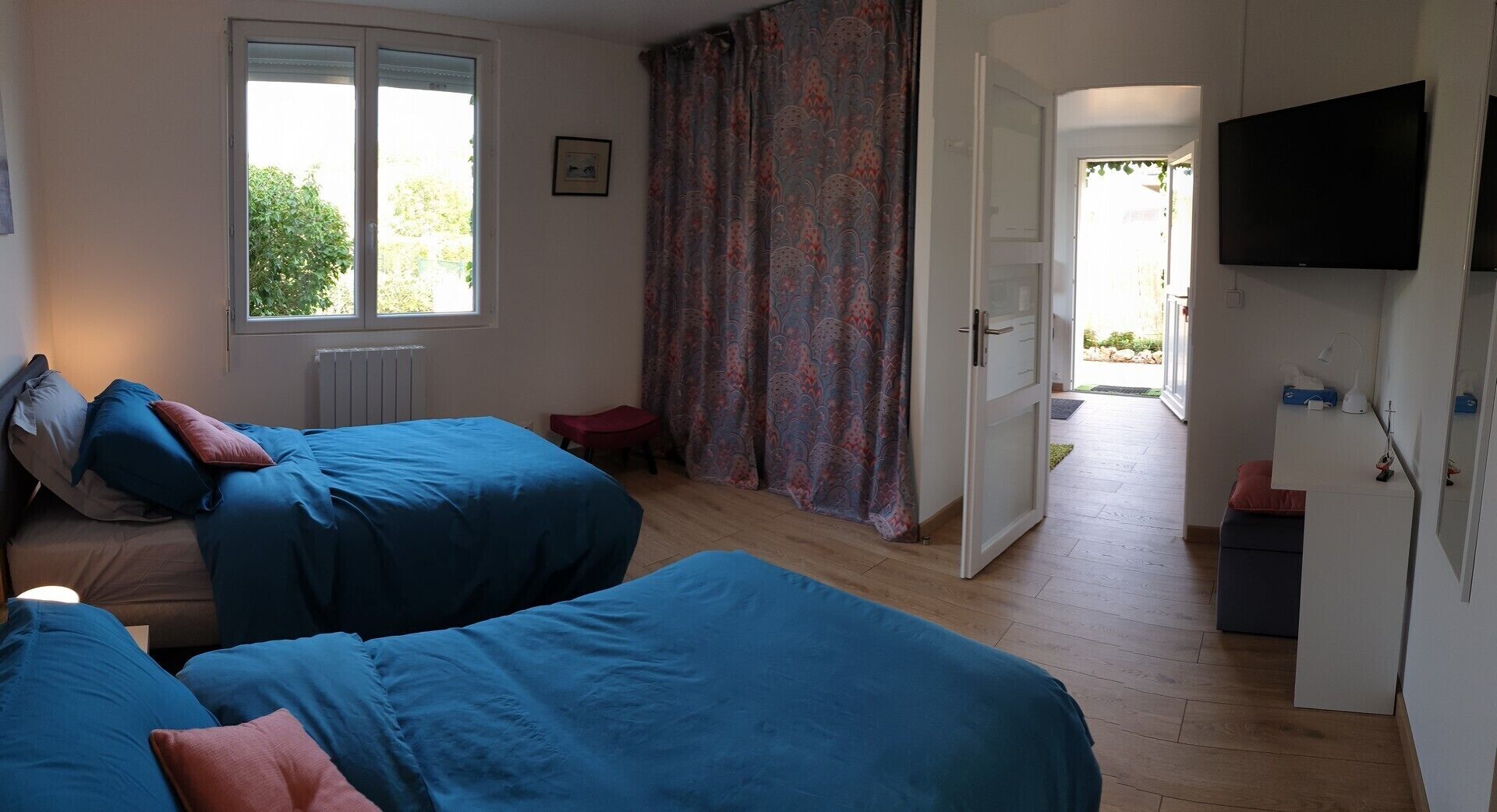 Quarto com duas camas, televisão e vista para o exterior.