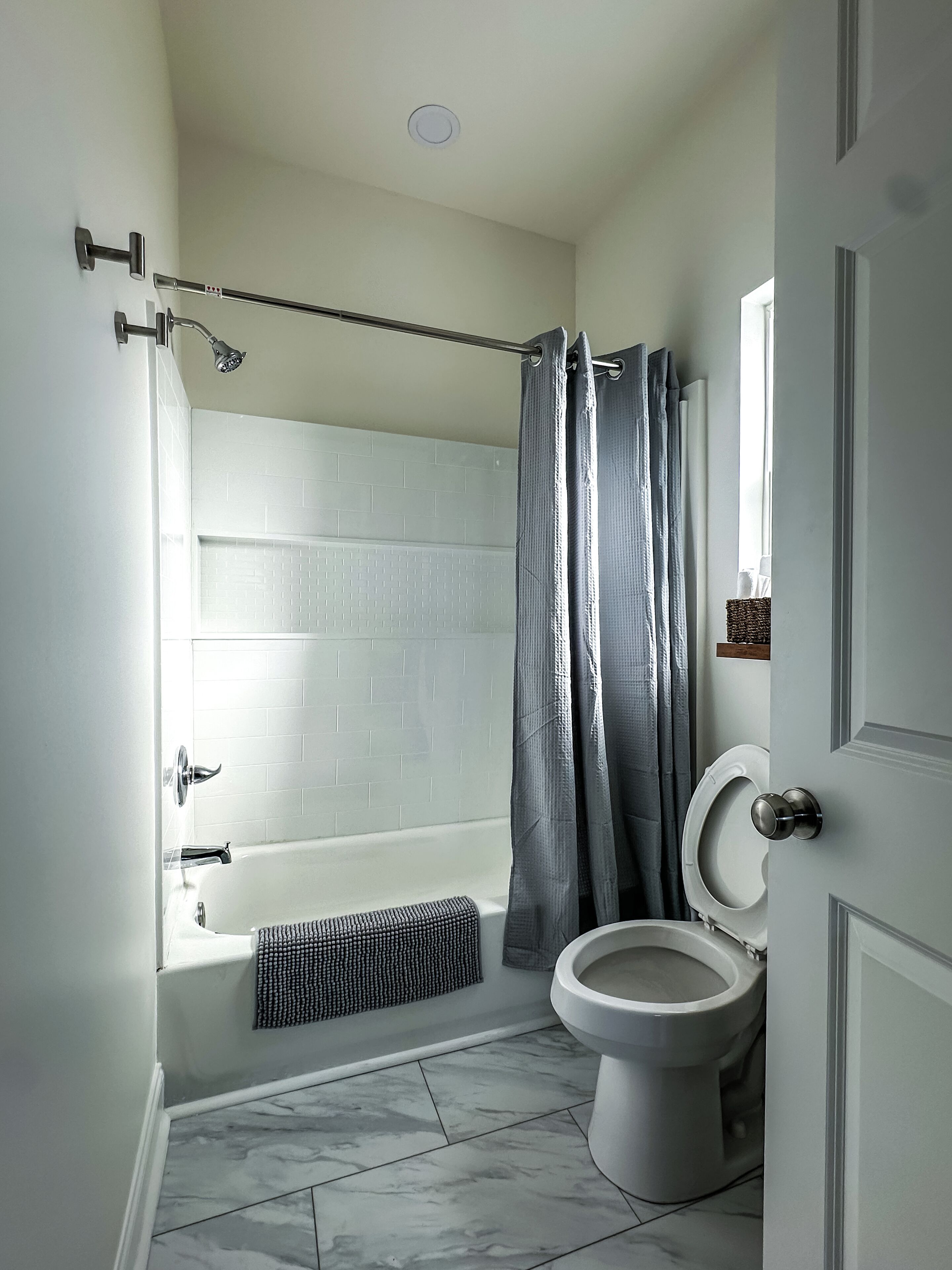 A bathroom with a bathtub, toilet, and shower curtain.