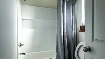 A bathroom with a bathtub, toilet, and shower curtain.