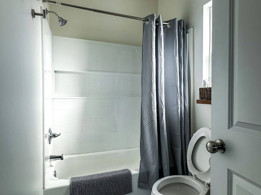 A bathroom with a bathtub, toilet, and shower curtain.