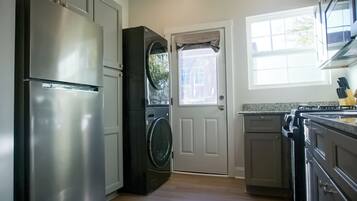 Une cuisine équipée d’un réfrigérateur en acier inoxydable, d’un lave-linge, d’une cuisinière et de placards.