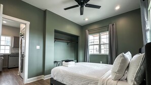 A bedroom with a bed, a ceiling fan, a window with curtains, and a view of the outside. - StayAE - Flamingo House (Baton Rouge)