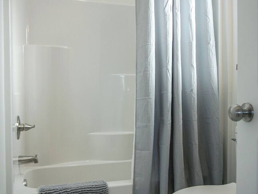 A bathroom with a walk-in shower, a bathtub, a toilet, and a towel rack.