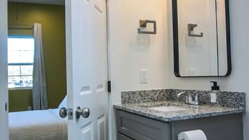 Une salle de bain comprenant un meuble-lavabo, des toilettes et un espace douche.