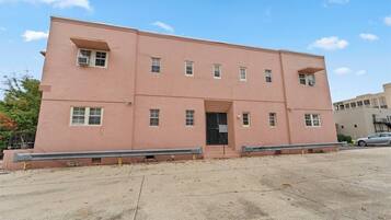 A pink building with a flat roof, multiple windows, and a central entrance.