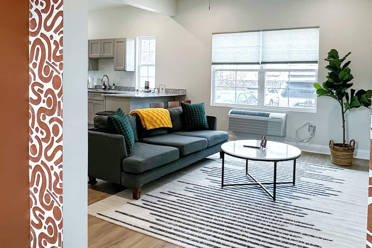 A modern living room with a gray sofa, a coffee table, and a patterned rug.