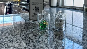 A kitchen counter with a welcome guide, two glass jars with ice, and a QR code. - StayAE - Flamingo House (Baton Rouge)