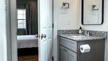 A modern bathroom with a marble floor, a sink with a faucet, a toilet, and a mirror with lights.