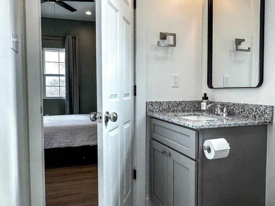 A modern bathroom with a marble floor, a sink with a faucet, a toilet, and a mirror with lights.