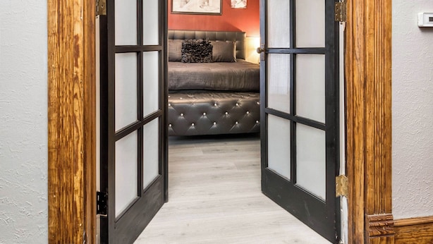A room with a bed, a sofa, and a wall-mounted light fixture. - Beautiful 3 bedroom uniquely designed home for small to large families! Pets ok! (Davenport)