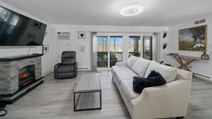 Una sala de estar moderna con chimenea, un sofá, una mesa de centro y un televisor montado en la pared.