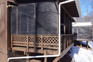 A covered outdoor area with a wooden deck and metal mesh screens.