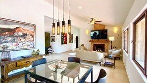 Ein modernes Wohnzimmer mit einem Glastisch, Sofas, einem Kamin und Kunstwerken an den Wänden.
