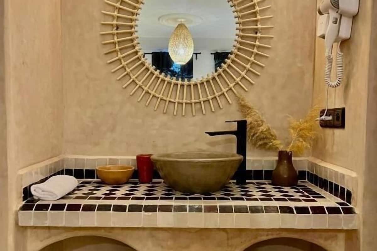 Un baño con un espejo grande, un lavamanos y un secador de pelo montado en la pared.
