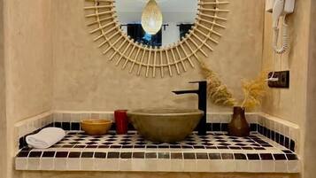 A bathroom with a large mirror, a sink, and a hairdryer mounted on the wall.