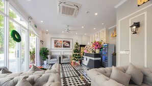 Een hotellobby met een zwart-wit schakeerdvloer, twee banken, een kerstboom en een koffiehoek.