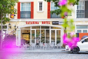 A hotel with a sign reading "Catarina Hotel" and "Milano Coffee" on the facade.
