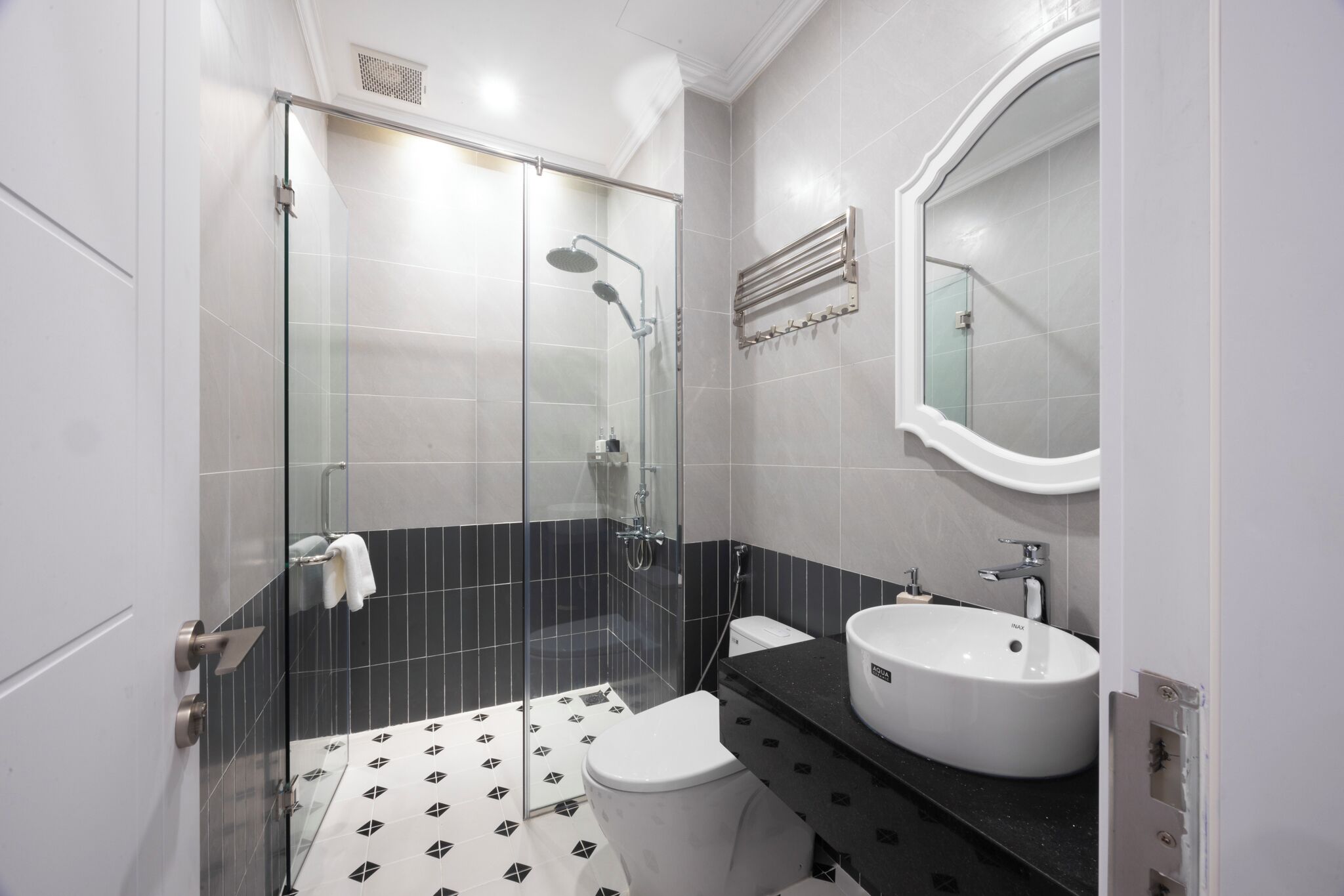 Une salle de bain moderne avec une douche à parois de verre, des toilettes blanches et un lavabo avec un miroir au-dessus.