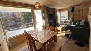 A cozy cabin interior with a wooden dining table, chairs, a sofa, and a TV. - 50m from ski slopes, 3rd floor, balcony, fireplace or stove, ski locker, 40m², Vars (Vars)