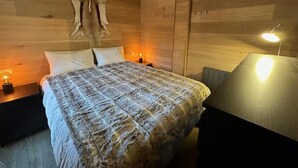 A wooden room with a bed, a nightstand, a lamp, and a wall-mounted light fixture. - 50m from ski slopes, 3rd floor, balcony, fireplace or stove, ski locker, 40m², Vars (Vars)