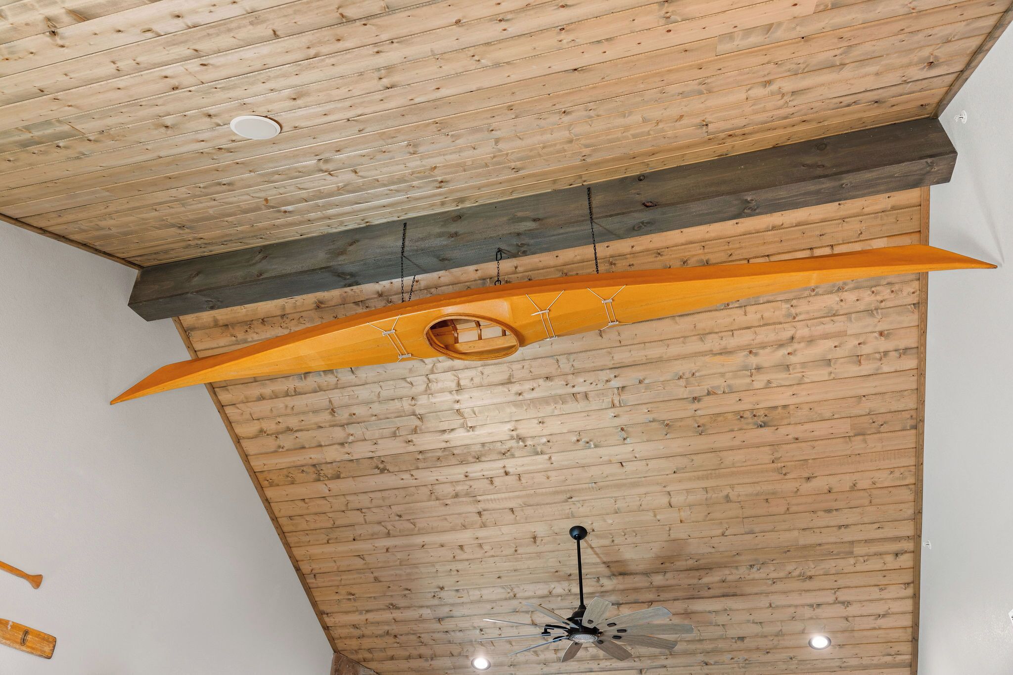 Una habitación con techo de madera, un ventilador de techo y una lámpara colgante.
