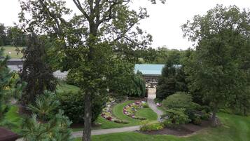 A landscaped garden with a winding path, mature trees, and a building with a green roof in the background.