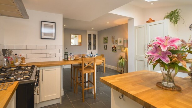 A modern kitchen with a central island, wooden chairs, and a dining table. - Colourful, homely 2 bed terrace - Pass the Keys (Shrewsbury)