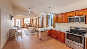 A spacious kitchen with wooden cabinets, a stainless steel microwave, and an oven. There is a dining area with a table and chairs.