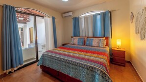 A bedroom with a bed, curtains, a nightstand, and a ceiling fan.