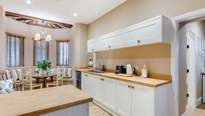 Une cuisine moderne avec des meubles blancs, un plan de travail en bois et un coin repas comprenant une table et des chaises.