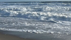 A beach with waves crashing onto the shore under a clear sky.