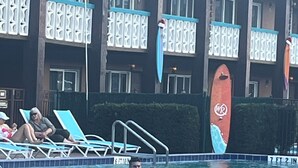 A swimming pool with lounge chairs and a building with balconies in the background.