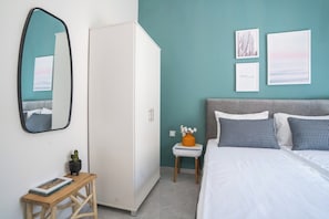 A bedroom with a bed, a wardrobe, a mirror, and wall art.
