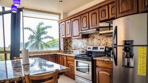 Una cocina con armarios de madera, un refrigerador de acero inoxidable, una estufa y una encimera de granito.