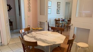 A dining area with a marble table, wooden chairs, and a white stool. - Apt. Biarritz Rés Carlton, Grande plage (Biarritz)